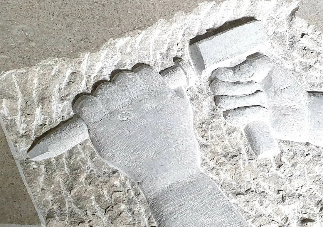 Kamnit relief dveh rok z dletom in kladivom, vklesan v kraški apnenec