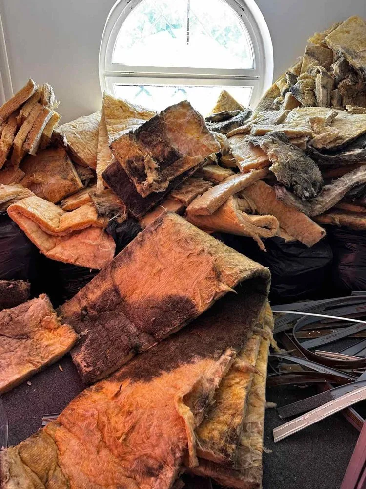 Izruvana mineralna izolacija, naložena ob polkrožnem oknu prostora.