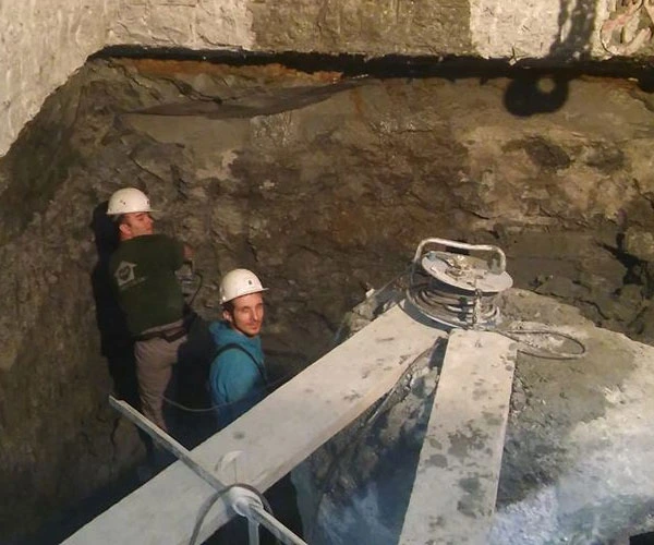 Dva delavca v zaščitnih čeladah v izkopu ob betonskem temelju