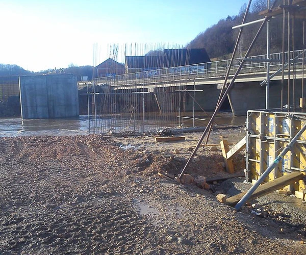 Gradbišče mostu z opažem in armaturo ob reki