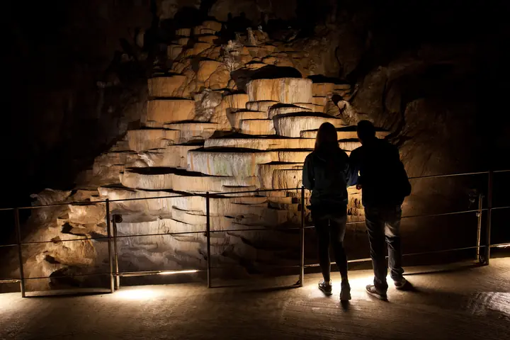 Visitors in front of rimstone pools in a Karst cave